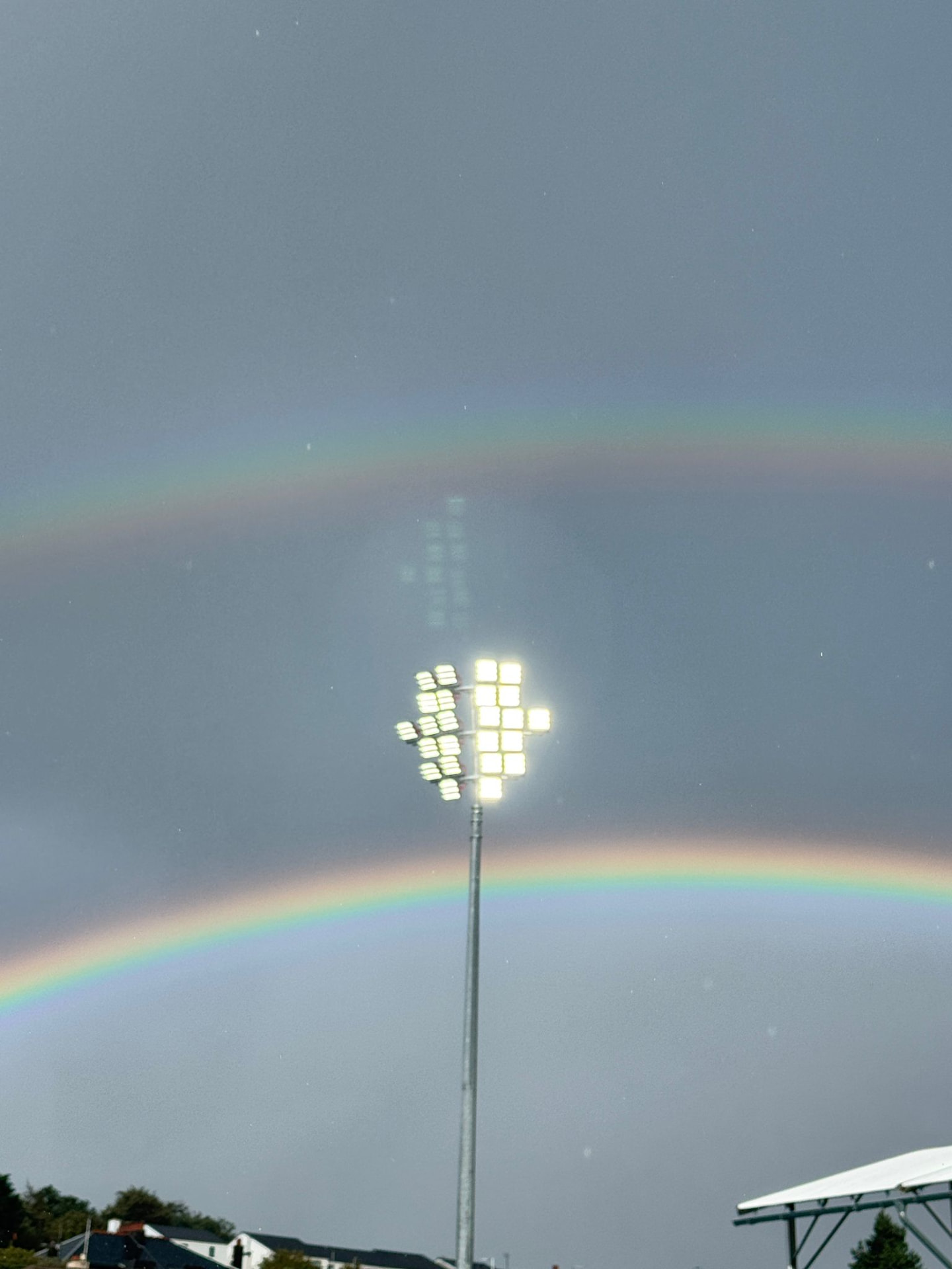 Scotstoun floodlight mast lit under a double rainbow